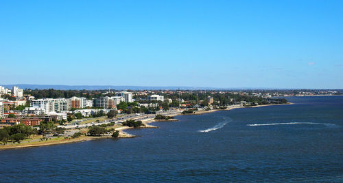 Aerial view of sea and cityscape against clear blue sky