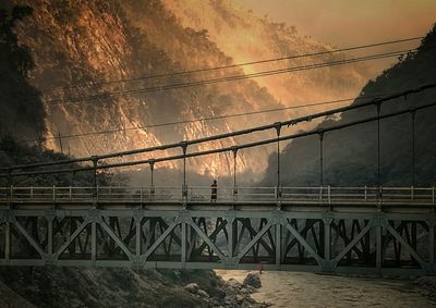 Bridge over river against sky during sunset