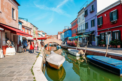 Boats moored in canal amidst buildings against sky