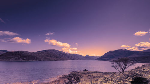 Scenic view of sea and mountains against sky during sunset