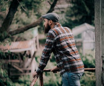 Young man standing against trees