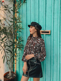 Woman looking away while standing against blue wall