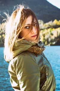 Portrait of beautiful woman standing against river