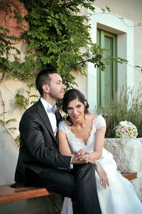 Portrait of bride sitting with bridegroom on bench