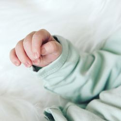 Close-up of baby hand on bed