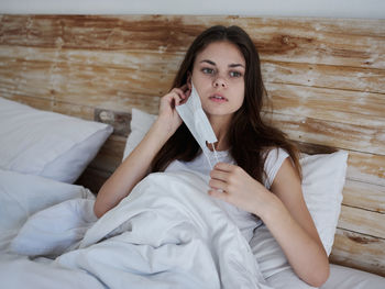 Portrait of young woman sitting on bed