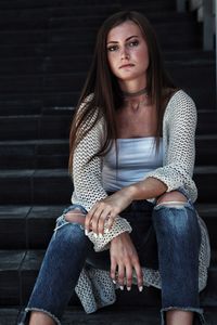 Portrait of beautiful young woman sitting on steps