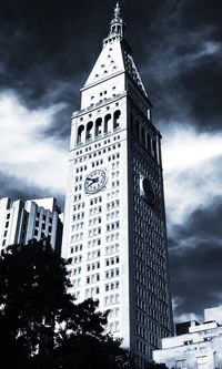 Low angle view of skyscrapers against cloudy sky