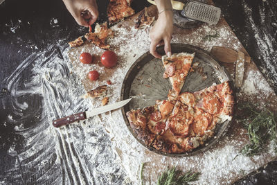 Pizza and hands top view with flour, dark background and toning