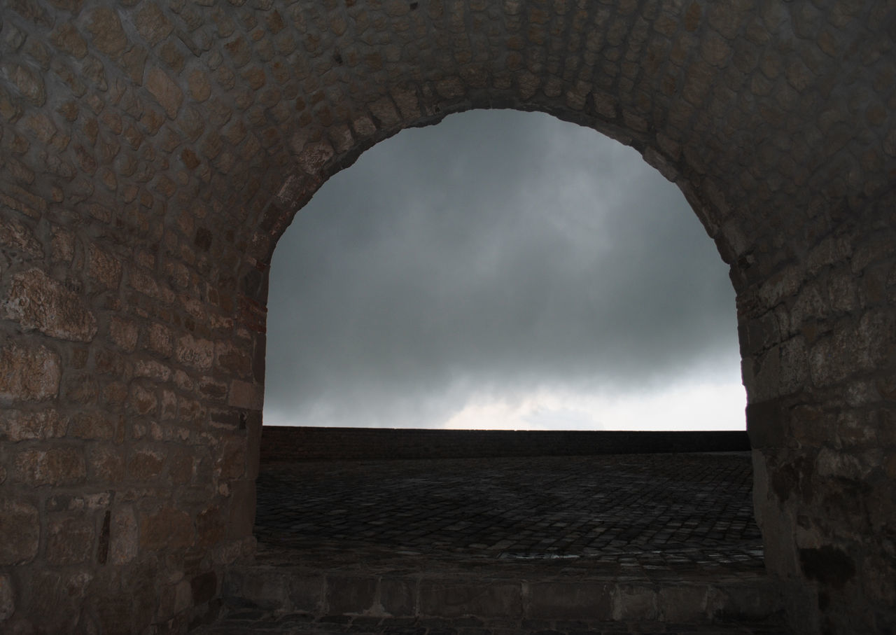 LOW ANGLE VIEW OF HISTORIC BUILDING AGAINST SKY SEEN THROUGH ARCH WINDOW