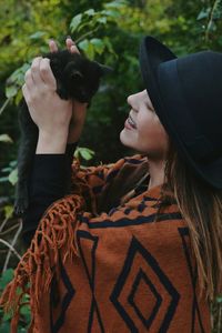 Woman in hat holding cat 