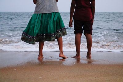 Low section of women and man standing at beach