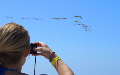 Low angle view of woman flying against clear blue sky