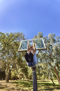 Low angle view of man playing basketball on court at park