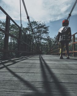 Rear view of man on bridge against sky