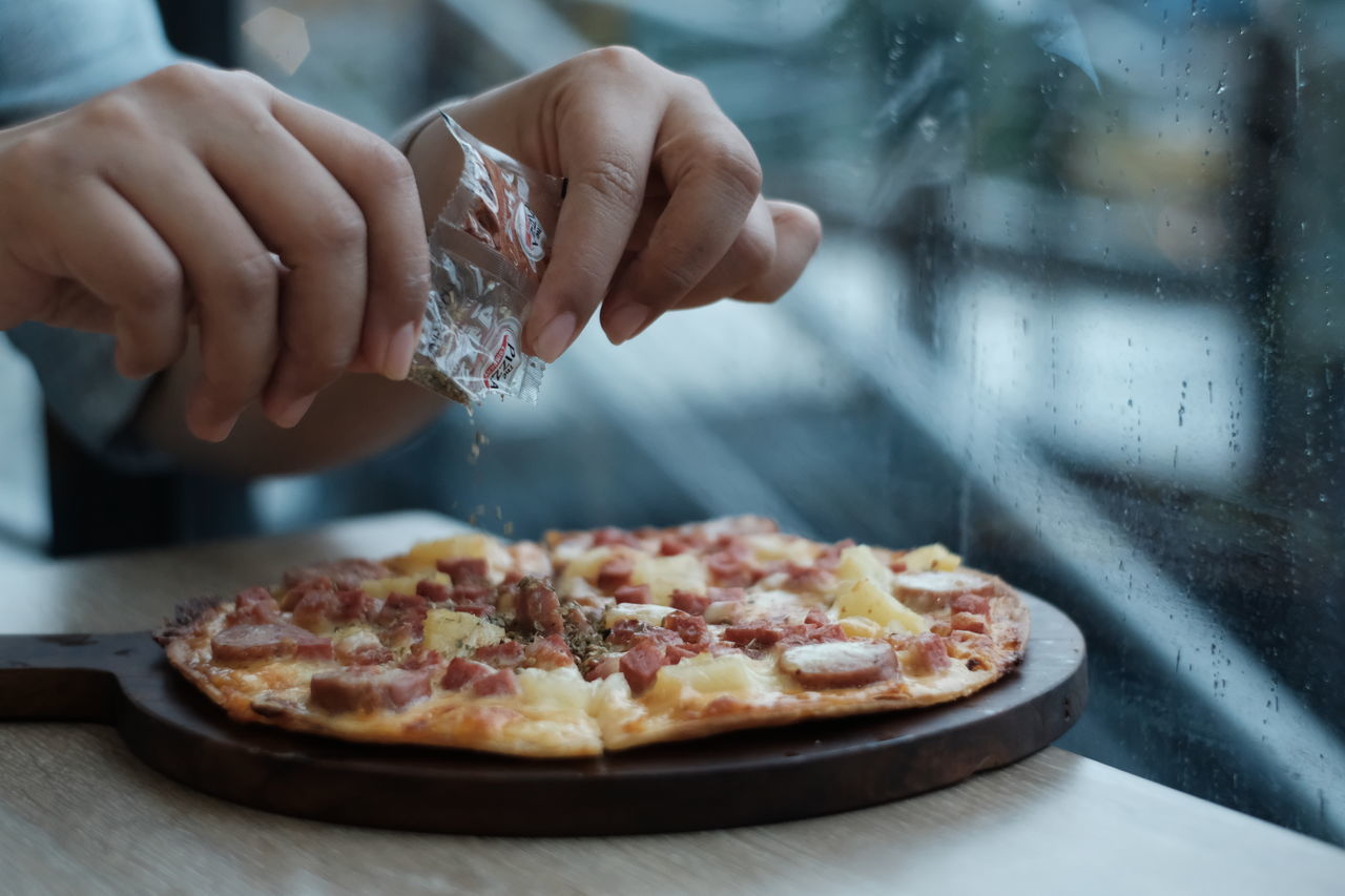 CLOSE-UP OF PERSON PREPARING PIZZA