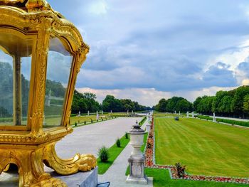 View of golden lantern and palace garden against cloudy sky