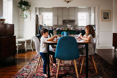 Young kids sitting at dining table doing arts and crafts together