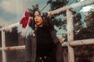 Portrait of smiling young woman standing against trees in winter