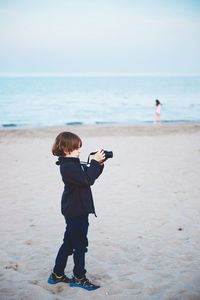 Full length of boy photographing from camera at beach