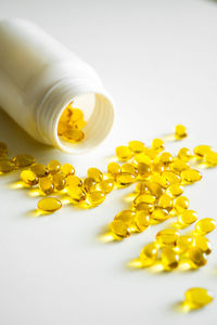 Close-up of pills spilling from bottle on white background