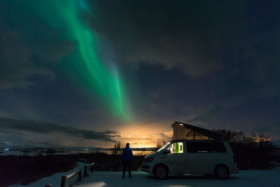 Cars on illuminated street against dramatic sky at night