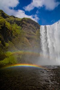 Scenic view of waterfall against sky whit rainbow