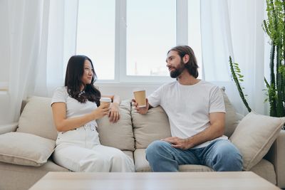 Couple using laptop while sitting on sofa at home