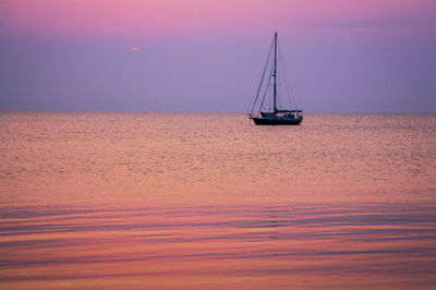 Sailboat sailing on sea against sky during sunset