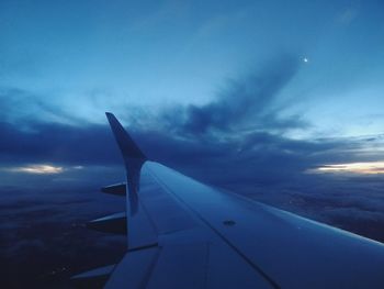 Close-up of airplane wing against cloudy sky