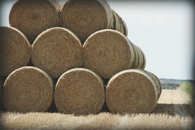 Stack of hay bales on field against sky