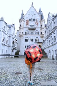 Rear view of person carrying umbrella in front of neuschwanstein castle