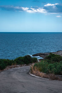 Scenic view of road by sea against sky