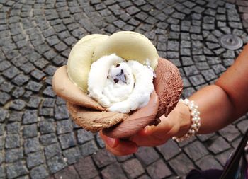 Cropped hand of woman holding ice cream on footpath