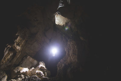 Low angle view of illuminated cave against sky at night