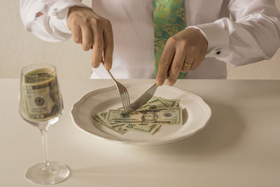Close-up of hand holding cup on table