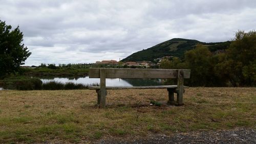 Bench by tree against sky