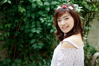 Portrait of smiling young woman against plants