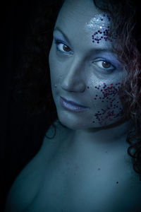 Close-up of woman wearing mask against black background