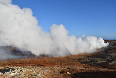 Smoke emitting from volcanic landscape against sky