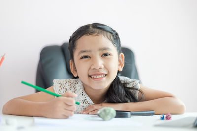 Portrait of smiling boy holding eyeglasses on table