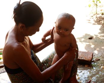 Grandmother bathing granddaughter in water