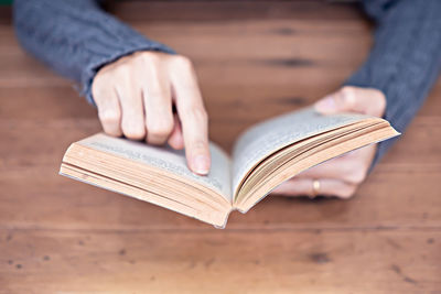 Midsection of woman reading book on table