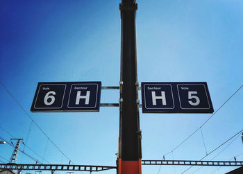 Low angle view of road sign against blue sky