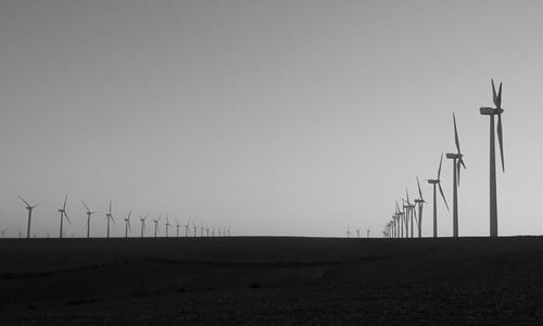 Windmills on landscape against clear sky