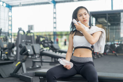 Young woman sitting on bench at gym