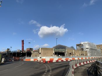 Road by buildings in city against sky