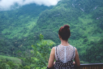 Rear view of woman standing in balcony against mountain