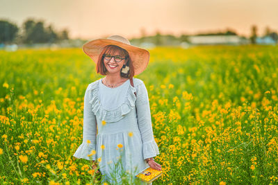 Full length of smiling young woman standing in field