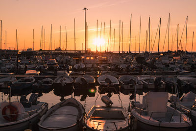 Boats moored at harbor during sunset